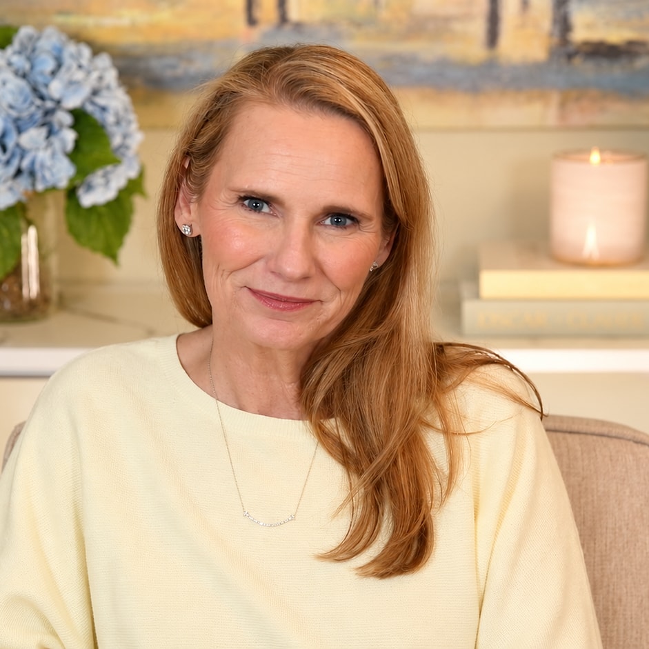 Jennifer Cook, seated at her desk between two vases of blue hydrangeas